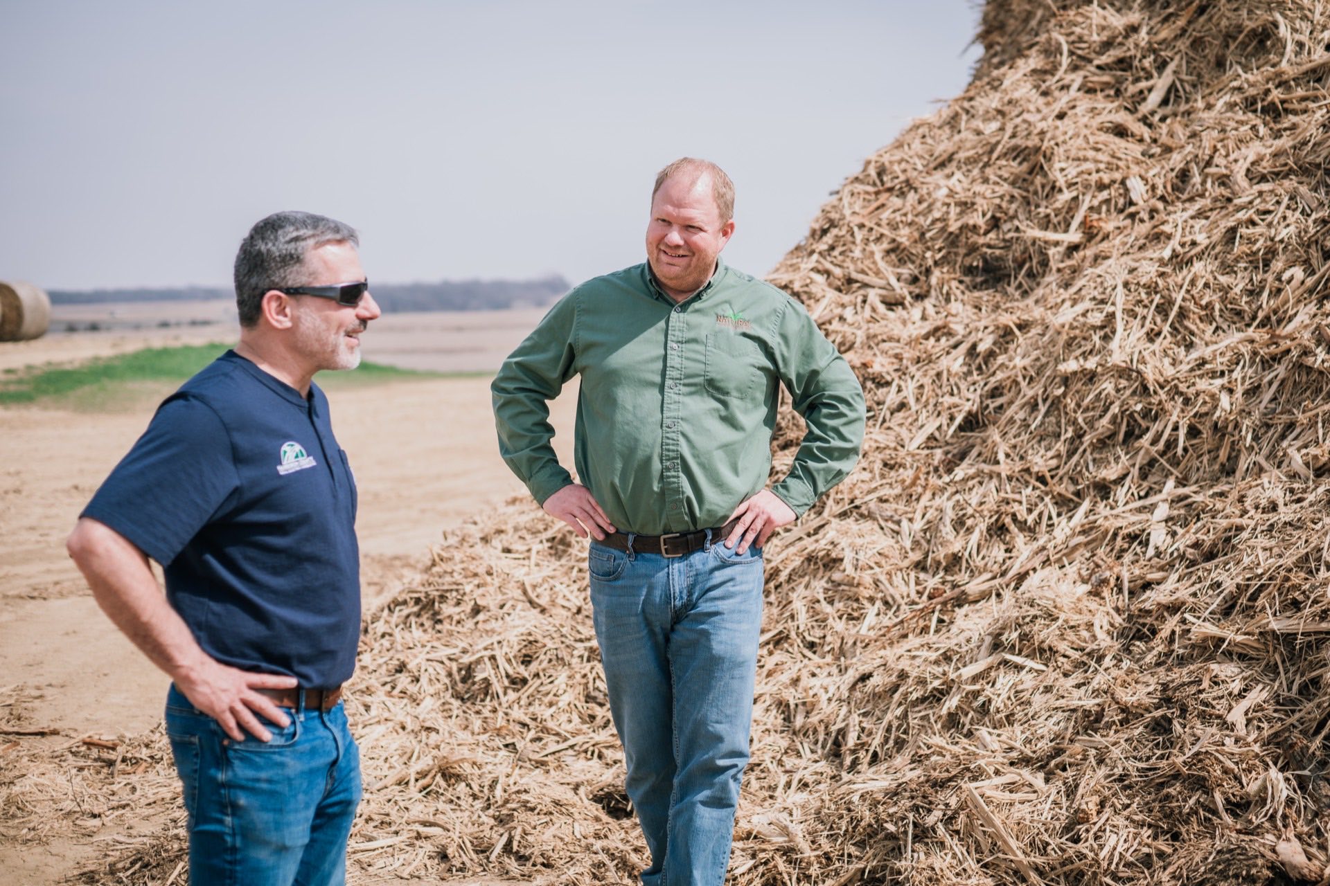 Two partners at the feedstock pile at the WINR Center